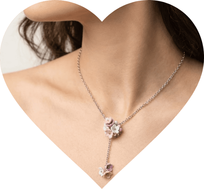Femme portant un collier floral artisanal en argile polymère et chaîne fine en acier inoxydable.