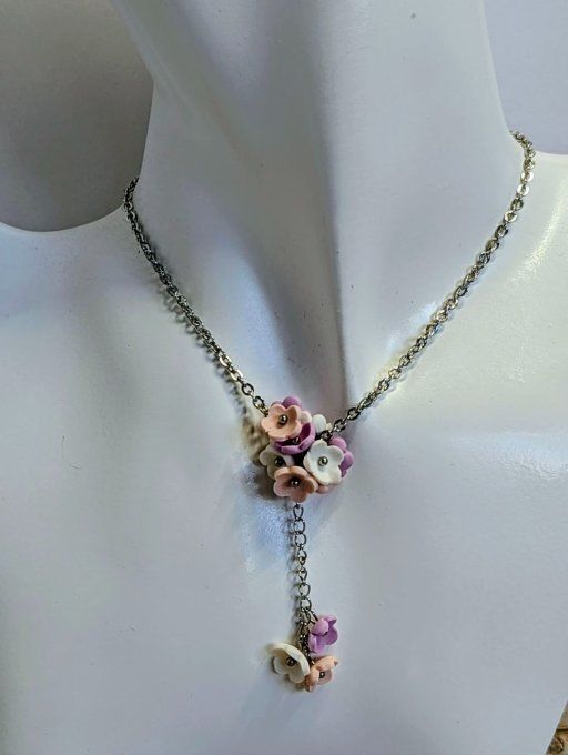 Collier lariat fleurs en argile polymère lilas et rose sur buste de présentation blanc.