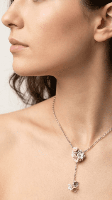 Femme portant un collier floral artisanal en argile polymère et chaîne fine en acier inoxydable.
