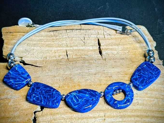 Collier artisanal bleu saphir en argile polymère composé de perles géométriques plates, monté sur un