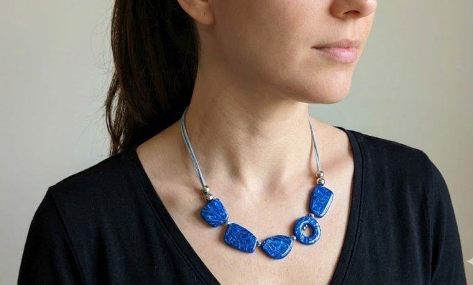 Collier artisanal bleu saphir en argile polymère composé de perles géométriques plates, monté sur un