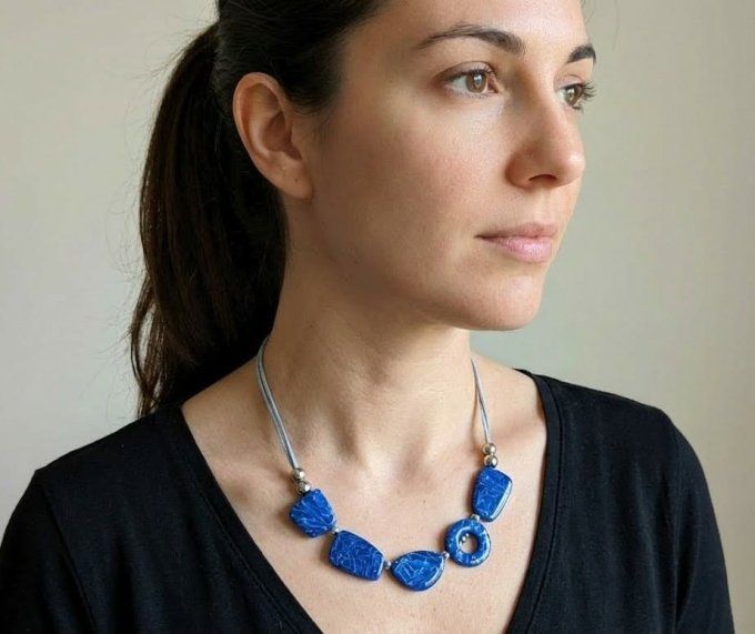 Collier artisanal bleu saphir en argile polymère composé de perles géométriques plates, monté sur un