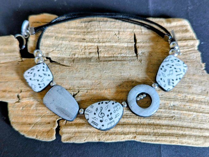 Collier artisanal en pâte polymère grise avec motifs de notes de musique et perles en acier inoxydab